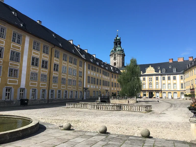 Innenhof der Heidecksburg in Rudolstadt: gelbe Barockflügel mit grauem Dach, Schlossturm mit grüner Haube und blauer Himmel
