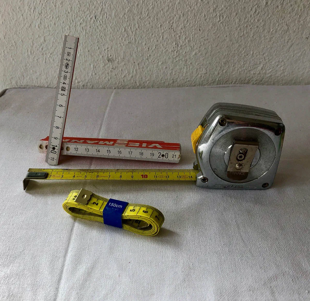 Ungeeignete Messgeräte: ein kurzer, dünner Klappmaßstab, ein Stahlbandmaß und ein aufgerolltes Schneidermaßband